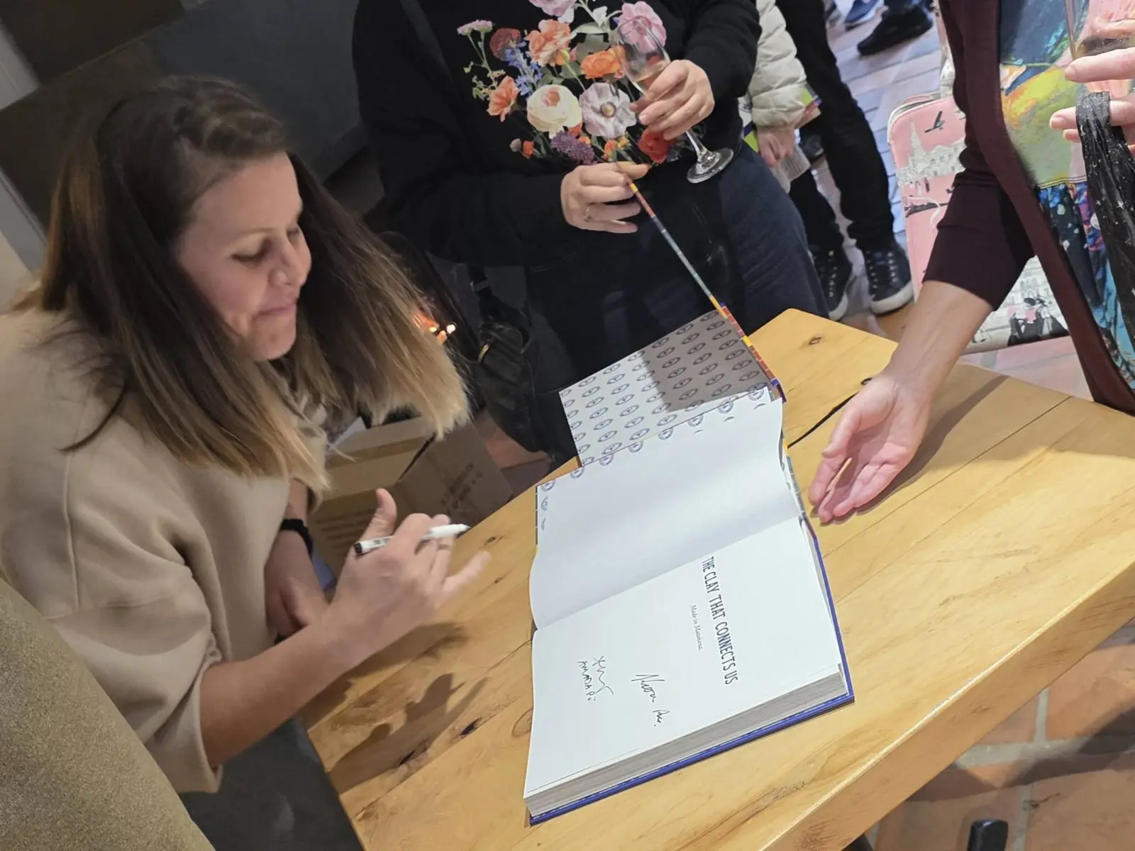 Signing the title page of The Clay That Connects Us